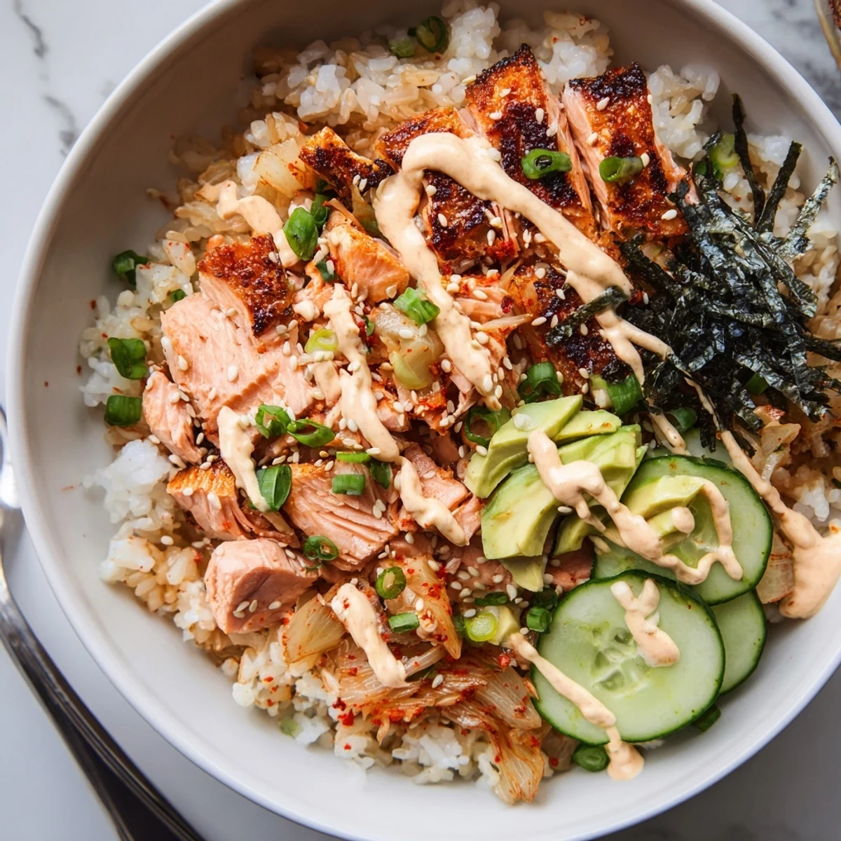 Crispy Salmon Rice Bowl garnished with spicy mayo, kimchi, and fresh avocado slices.  