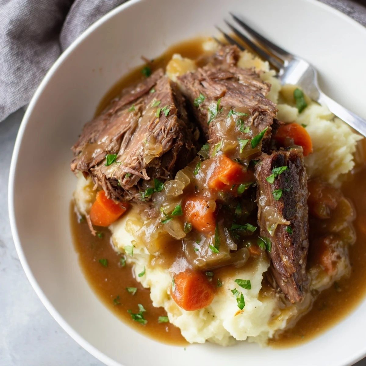 Tender Slow Cooker Pot Roast served over creamy mashed potatoes and rich gravy.  