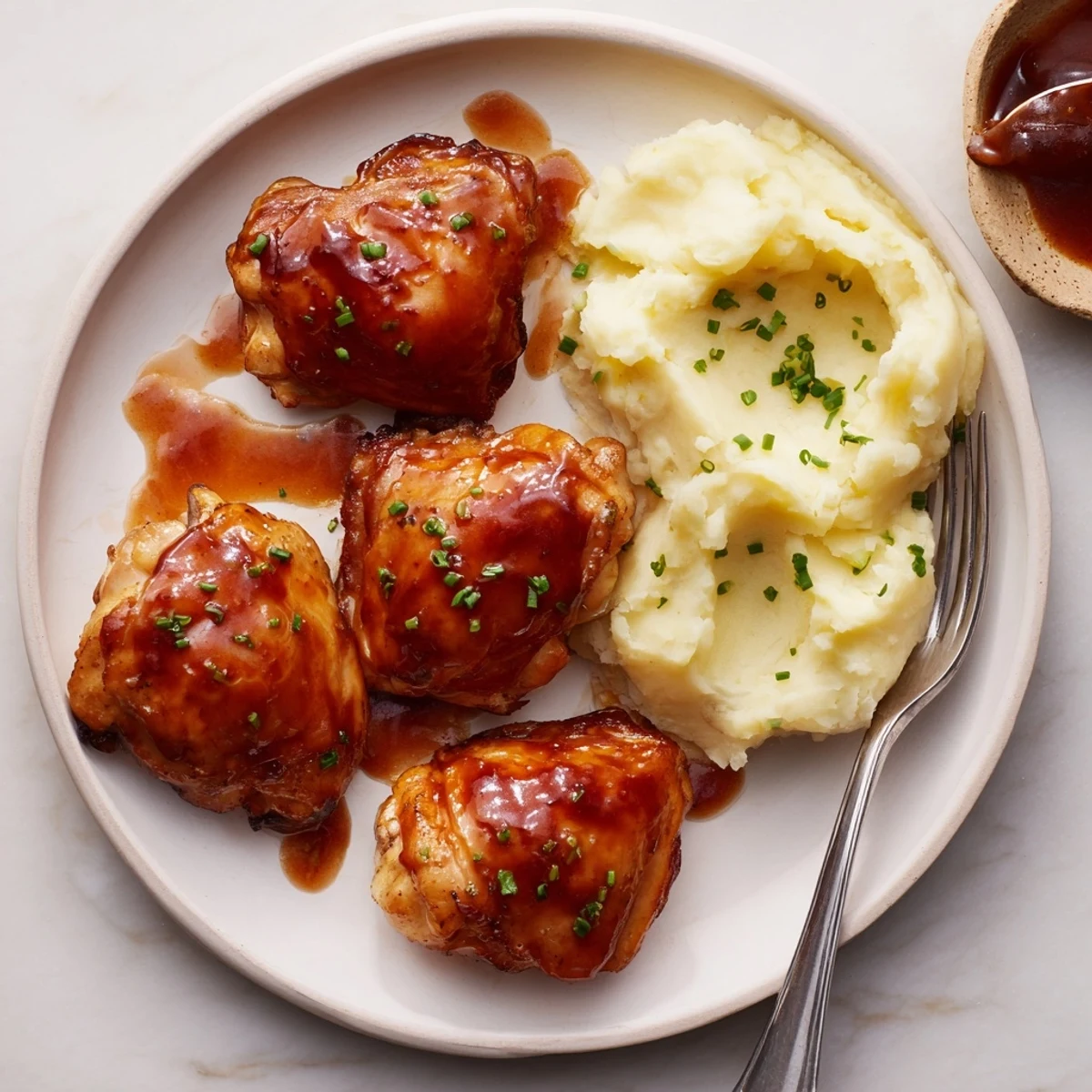 Sizzling honey BBQ chicken thighs surrounded by fluffy garlic mashed potatoes, perfect for family dinners.  