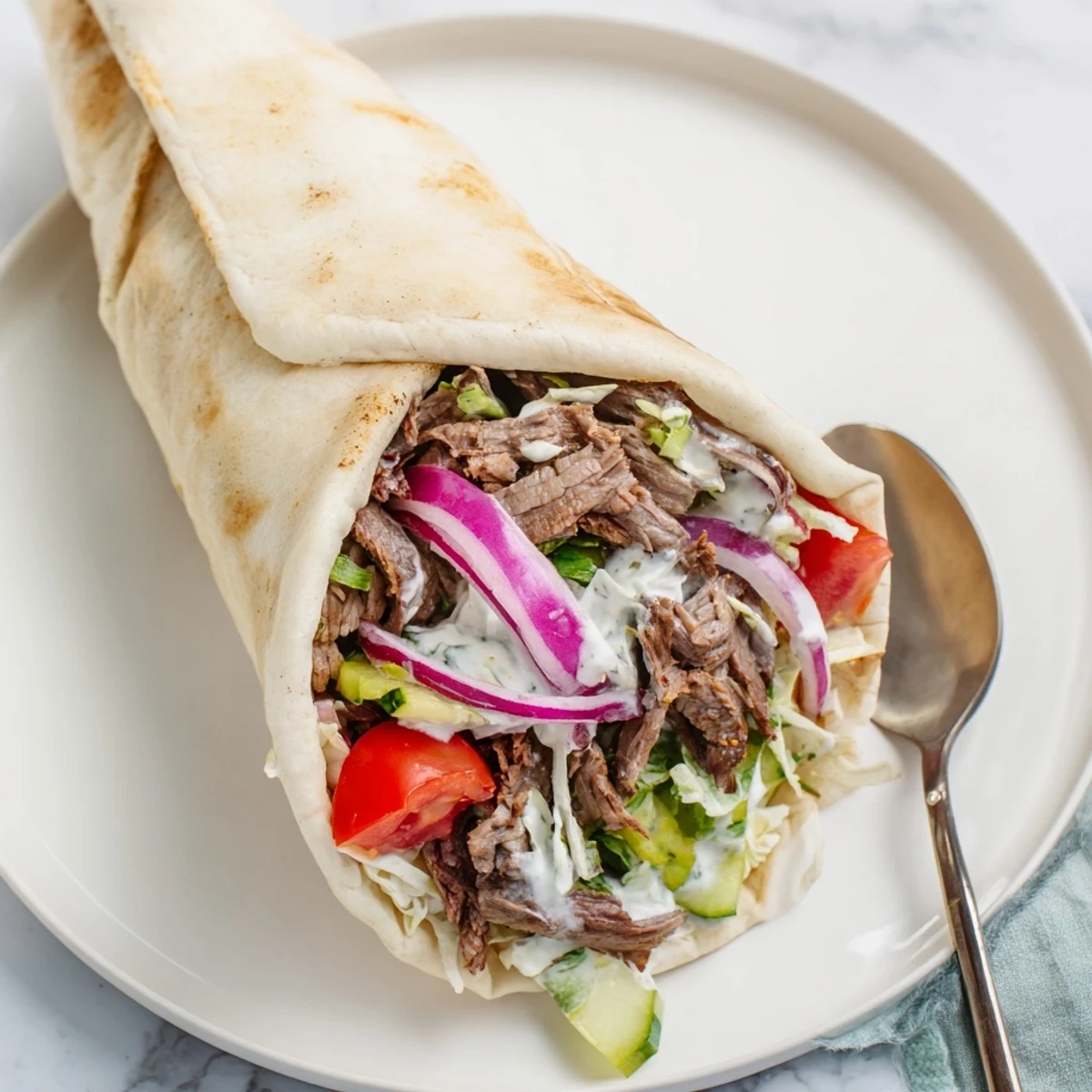 Savory beef shawarma wraps filled with lettuce, tomato, and zesty yogurt sauce.  