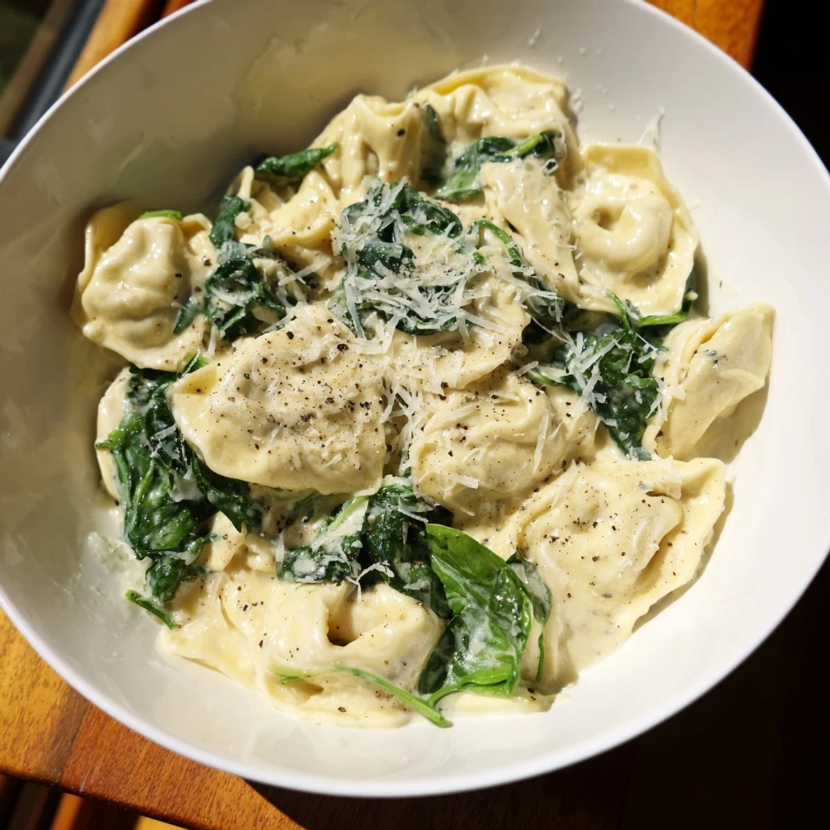 Creamy Spinach Alfredo Tortellini with fresh spinach, ready to serve with a sprinkle of Parmesan cheese.