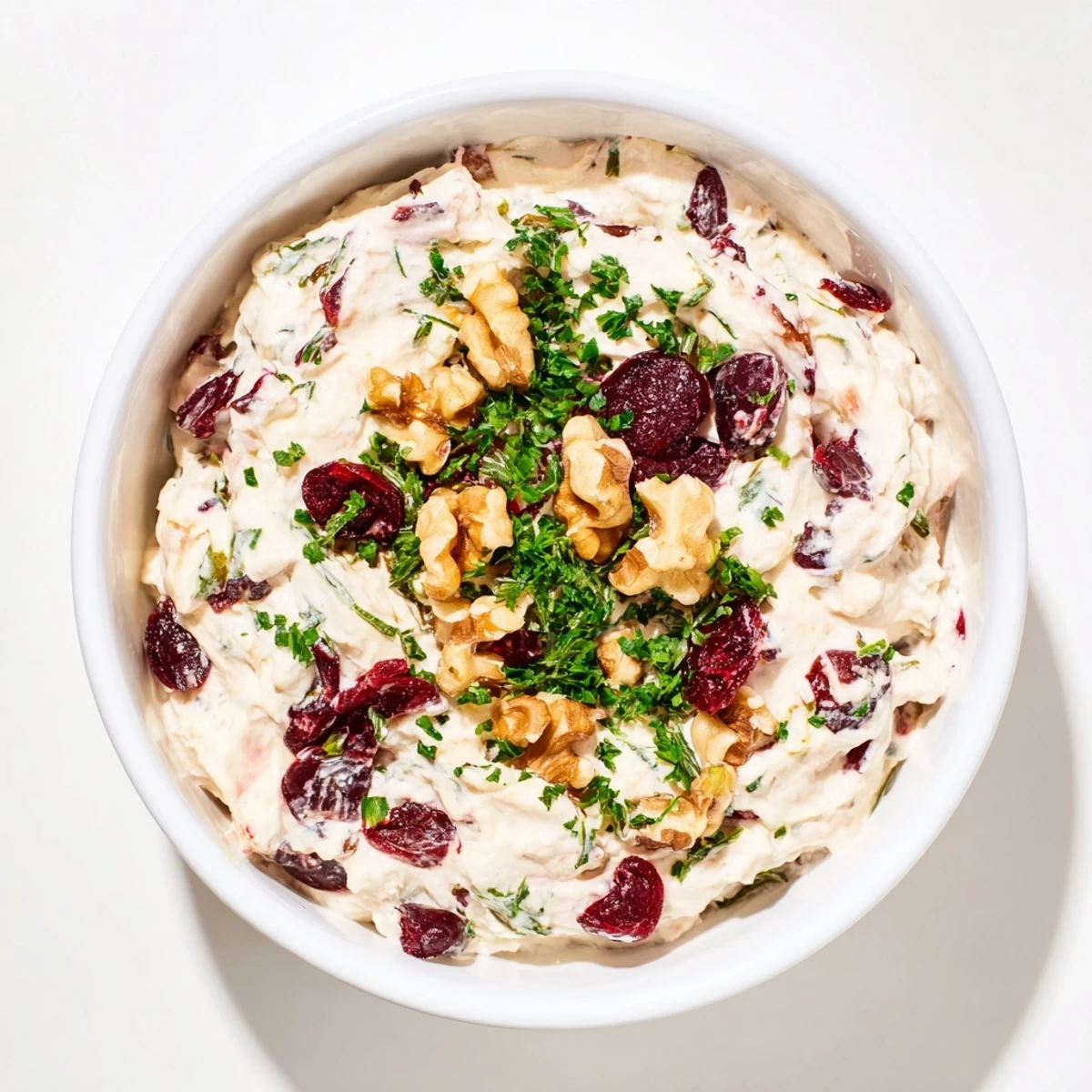 Creamy Lightened Holiday Cream Cheese Dip, perfect with crackers, garnished with cranberries and fresh herbs.