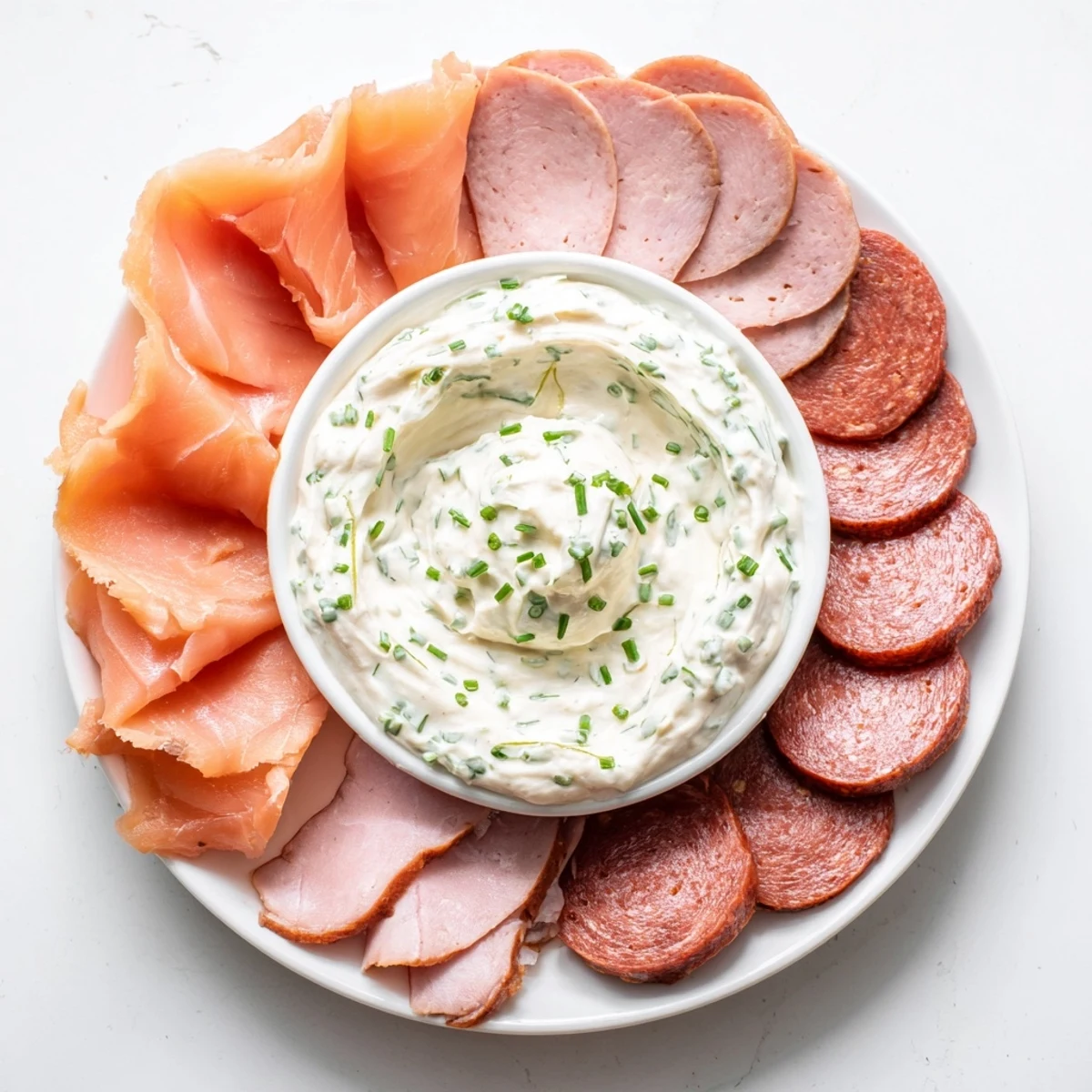 A beautifully arranged Compass Rose appetizer features diverse meats surrounding a creamy dip.