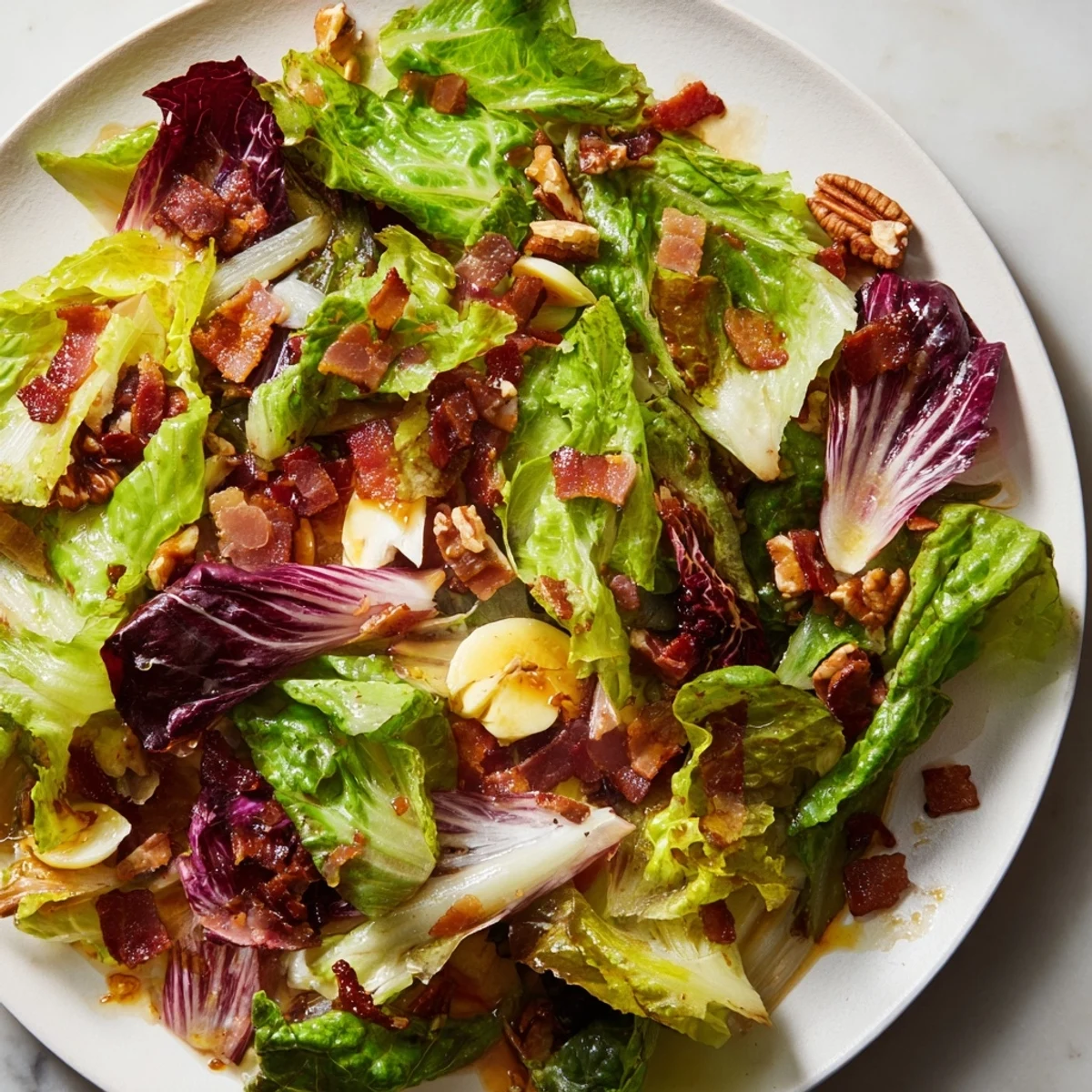 This American Bitter Greens Salad with Warm Bacon Dressing features wilted greens, glistening dressing, and crunchy bacon pieces.