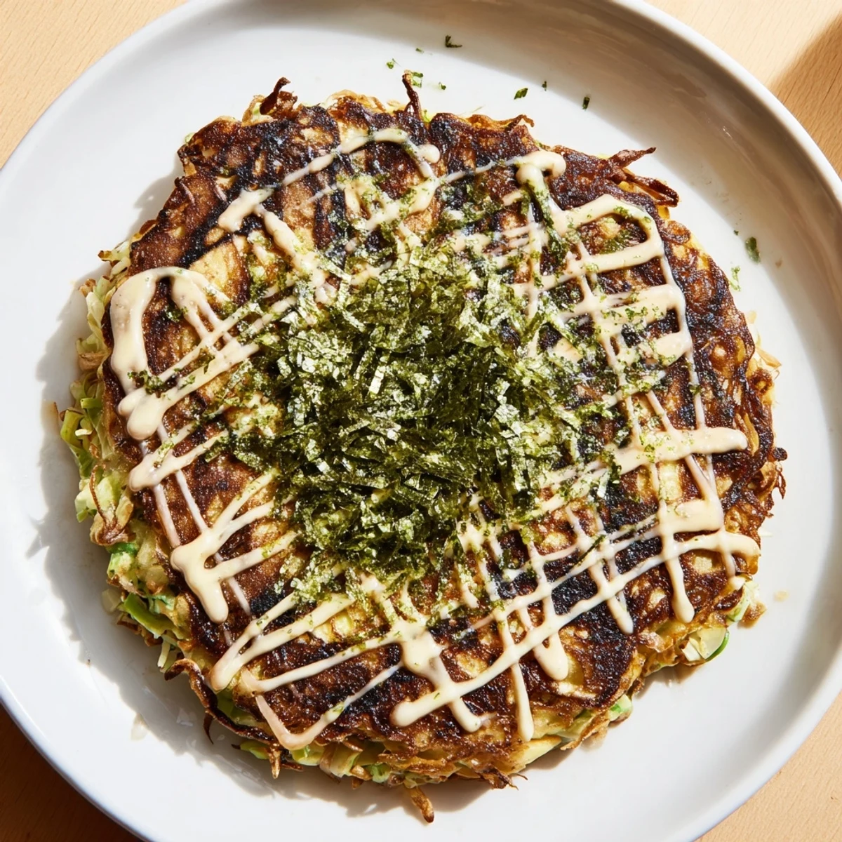 A savory Japanese Okonomiyaki pancake, topped with creamy mayonnaise and dancing bonito flakes, ready to eat.