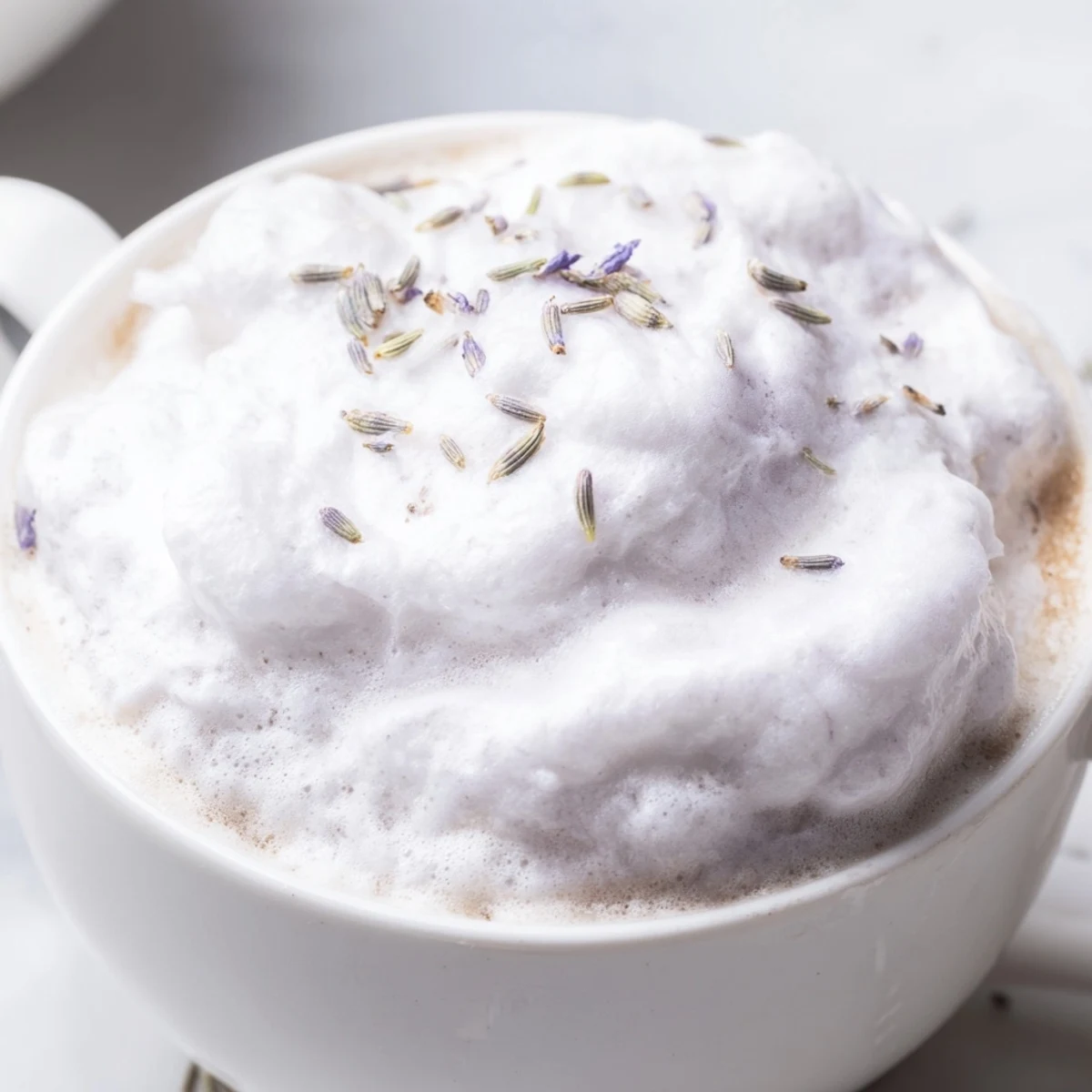Enjoy the visually appealing layers of an aromatic Whipped Lavender Latte, served in a warm mug.