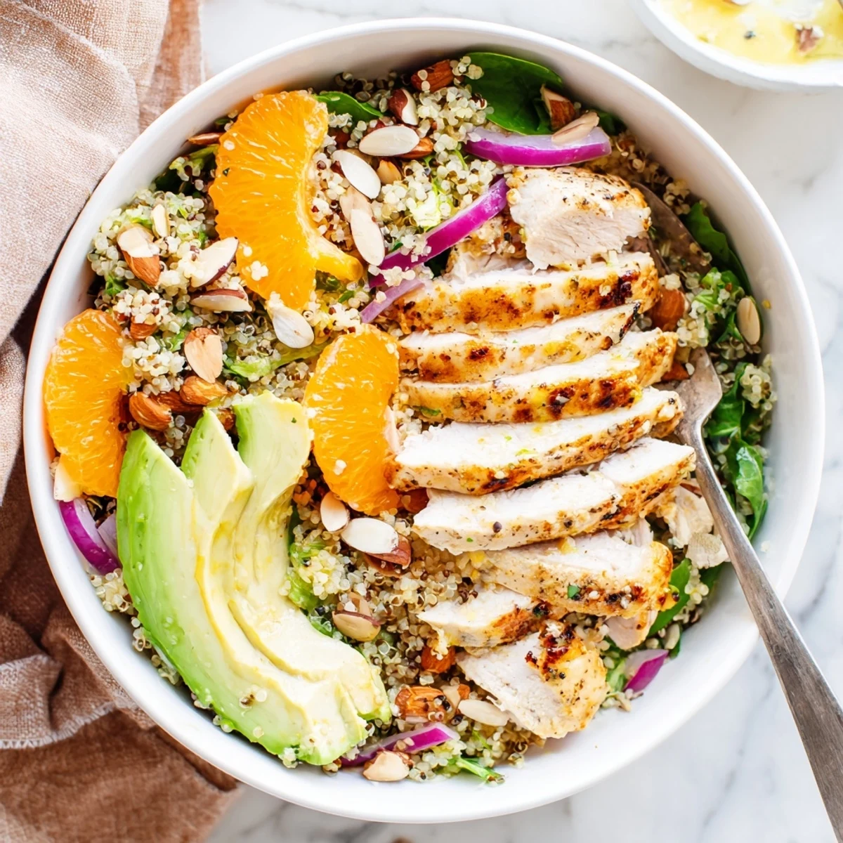 Grilled herb-marinated chicken sits atop fluffy quinoa and fresh greens in a vibrant Citrus Herb Chicken Salad Bowl.