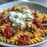 Al dente pasta tossed with juicy tomatoes, silky burrata, and aromatic basil for a rich Italian-inspired meal.  