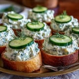 Classic Kentucky Benedictine spread served on toasted bread rounds, topped with thin cucumber slices and herb garnish.  