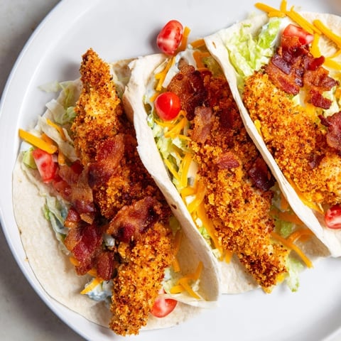 Golden-brown Crispy Chicken Bacon Ranch Wrap, filled with bacon and cheese, awaits a delicious bite.