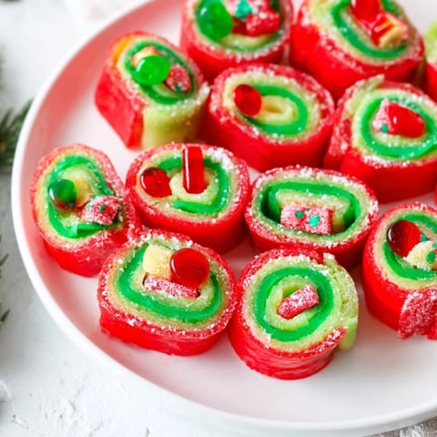Festive Christmas Fruit Rollup Sushi rolls: colorful treats with sprinkles and gummy worms inside.