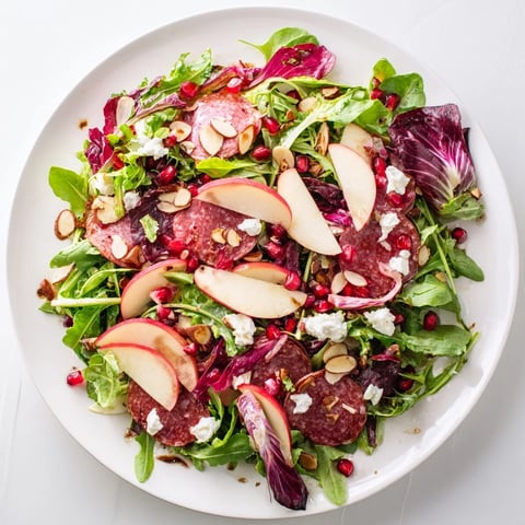 Vibrant Hot Girl Christmas Salad with salami, juicy pomegranate seeds, and a creamy cheese crumble.
