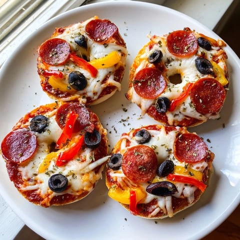 Golden, bubbly cheese covers warm mini bagel pizzas, a quick and easy snack ready to enjoy.
