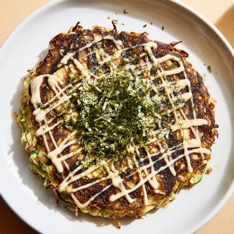 A savory Japanese Okonomiyaki pancake, topped with creamy mayonnaise and dancing bonito flakes, ready to eat.