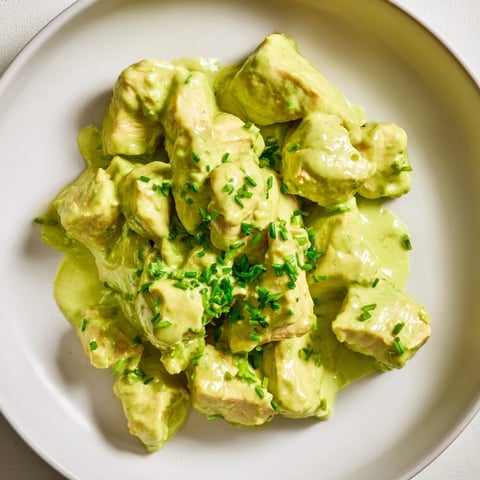 Freshly grilled chicken chunks tossed with crisp cucumbers and creamy avocado ranch dressing over mixed greens in a salad bowl.