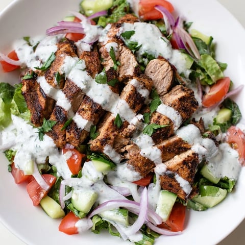 Vibrant Chicken Shawarma Salad with spiced grilled chicken, crisp cucumbers, tomatoes, and a creamy yogurt dressing served on a bed of greens.