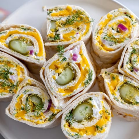 Colorful tortilla rolls filled with pickle and cheese, ideal for quick appetizers.  