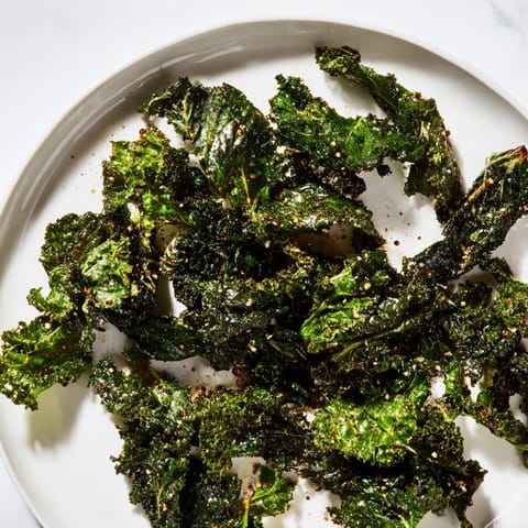 Freshly baked kale chips, delightfully crispy, seasoned with salt, pepper, and ready to enjoy.
