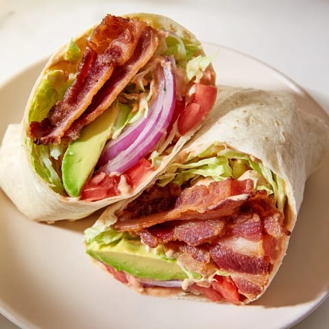Close-up of a zesty BLT wrap revealing layers of bacon, lettuce, and a creamy chipotle dressing.