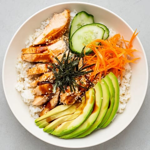 A beautifully arranged Japanese-Style Salmon & Chicken Rice Bowl with colorful toppings and sesame seeds.