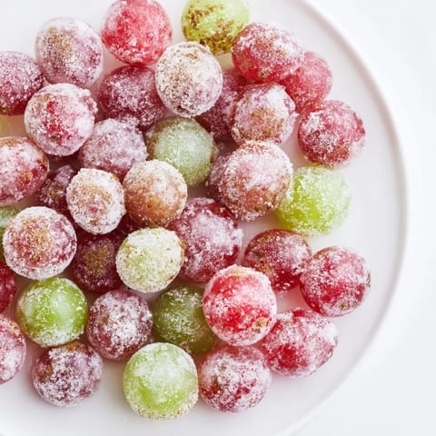 Sweet and frosty frozen grapes, perfect for a vegan snack, shining under the kitchen light.