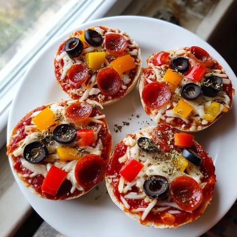 Homemade mini bagel pizzas loaded with pepperoni, cheese, and olives, perfect for a quick lunch.
