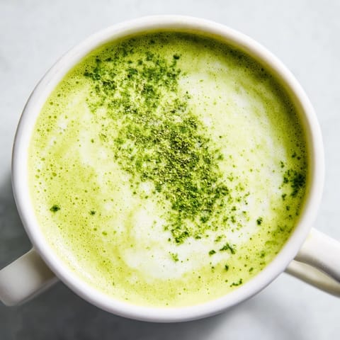 Steaming matcha green tea latte, showcasing a delicate foam layer, ready to be enjoyed.