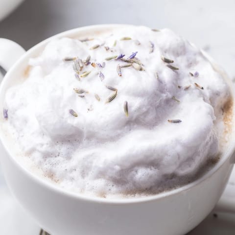 Enjoy the visually appealing layers of an aromatic Whipped Lavender Latte, served in a warm mug.
