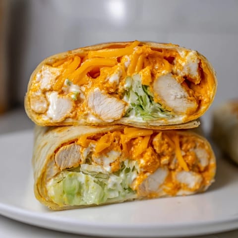 Two stacked Buffalo Ranch Chicken Wraps on a white plate with celery sticks and a small bowl of ranch dressing.