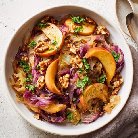A tangy German-inspired warm apple and sauerkraut skillet salad served alongside grilled kielbasa for a comforting dinner.
