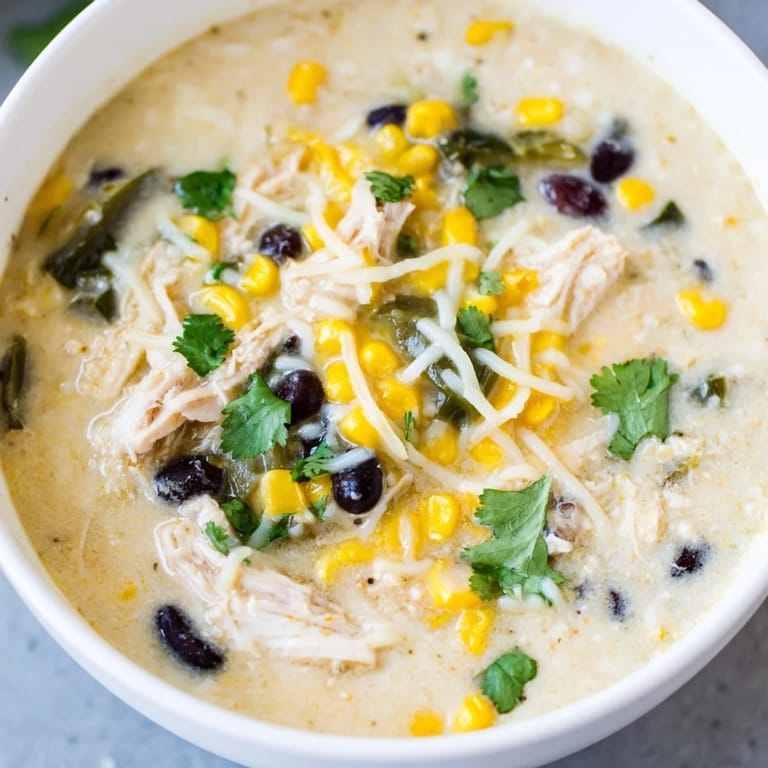 Enjoy a rich spoonful of Chicken Poblano Soup, with bits of black beans and melted cheese in a cozy meal.