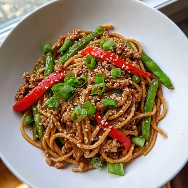 A close-up of savory sesame hoisin ground chicken pasta, perfectly coated linguine with visible veggies.