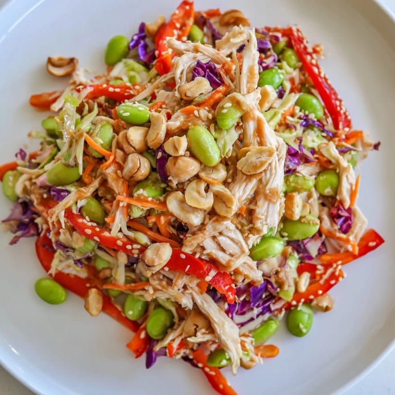 Close-up view of Edamame Crunch Chicken Salad, showcasing red bell pepper slices and green onions mixed with crunchy vegetables and tender chicken.